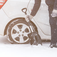 Person using snow shovel to dig out their car